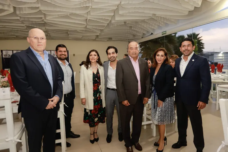 Grupo de empresarios posa de pie en un salón de eventos