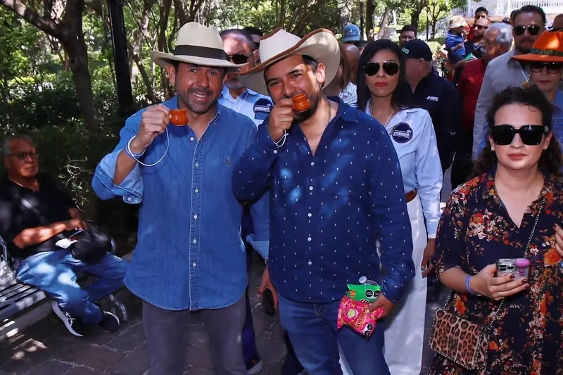 Asistentes con sombrero brindan durante una visita al aire libre